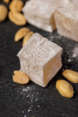 scattered oriental sweets Turkish delight with peanuts on a black slate board, closeup, side view