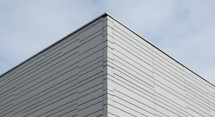 A close-up view of an architectural detail showcasing a corner of a modern building with a sleek, contemporary design. The building's facade features textured panels that catch the light.