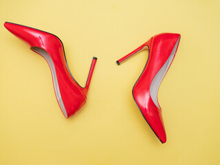 red women's stiletto heels lie on a yellow background