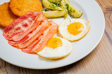 Breakfast features fried eggs, crispy bacon, golden hash browns, and fresh greens