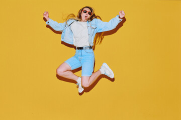 Obraz premium Woman in denim jacket leaps with unstoppable grin, energy fueling bold motion, energy reflecting bright attitude, boundless energy igniting joyful moment, bursting with youthful spirit