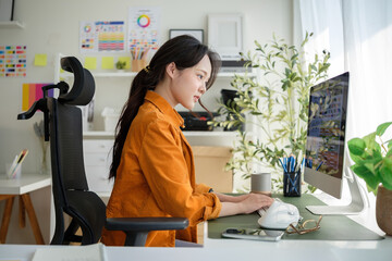 Focused graphic designer working on a desktop computer in creative studio.