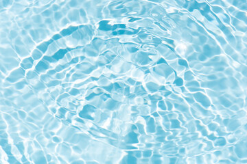 Blue water with ripples on the surface. Defocus blurred transparent blue colored clear calm water surface texture with splashes and bubbles. Water waves with shining pattern texture background.