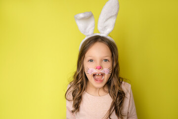 A surprised charming girl with curly hair, ears on head and a painted face in the guise of an Easter bunny