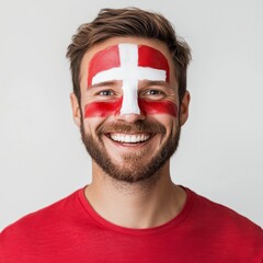 Portrait of a cheerful Swiss man with face painted in red and white cross of Switzerland flag, smiling confidently on light neutral background