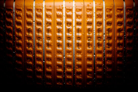 Wet shiny Veuve Clicquot LVMH champagne packaging box in stylish row arrangement with water drops and luxurious appearance with atmospheric light