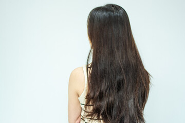 The back view of a woman showing her messy hair with visible split ends and damage.