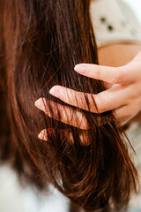 Fototapeta premium Combing with brush and pulls long hair. Daily preparation for looking nice, Long Disheveled Hair,Holding Messy Unbrushed Dry Hair In Hands. Hair Damage, Health And Beauty Concept.