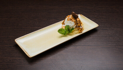 Dessert with puff pastry and ice cream drizzled with caramel on a plate