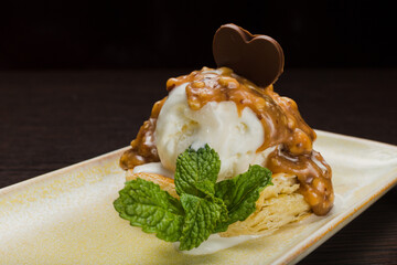 Dessert with puff pastry and ice cream drizzled with caramel on a plate