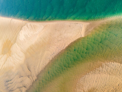 Aerial view of a sandy point jutting out into a blue ocean