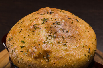 A pot with baked meat and a bread lid on a wooden stand