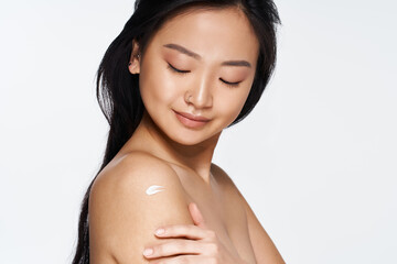 Capturing a moment of beauty and self care with a young Asian woman applying lotion