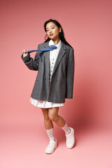 Fototapeta premium Young beautiful woman showcasing stylish outfit in vibrant studio with playful elegance