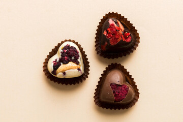 chocolate sweets in the form of a heart with fruits and nuts on a colored background. top view with space for text, holiday concept