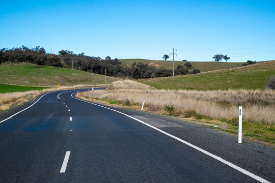 Regional road surrounded by hills and a clear blue sky