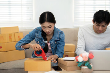 Logistics and Packagings. A couple meticulously preparing and packaging their online orders,...