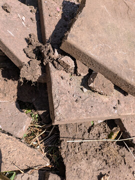 Close up of old broken pation pavement slabs dug up from house garden renovation DIY