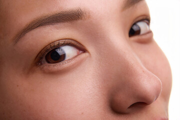 Fototapeta premium Cropped close-up portrait of young Korean woman with flawless, spotless skin, brown eyes, neat eyebrows, small perfect nose. Ideal features, plastic surgery, rhinoplasty, beauty treatment, skincare