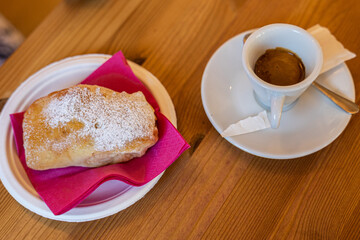 caffè espresso in tazza con dolce di pastafrolla ,con ripieno di marmellata, su un tavolo di legno, in un bar, di giorno
