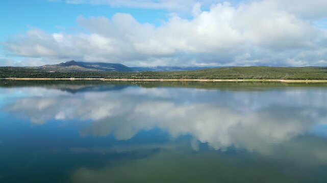Beautiful drone view landscape with a lake of calm waters and reflections of clouds in the water, El Atazar, Madrid