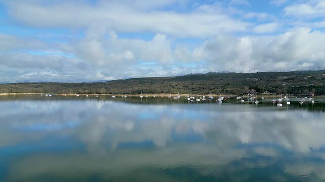 Beautiful lake next to the mountains with small pleasure boats at the foot of the houses, El Atazar, Cervera, Madrid.