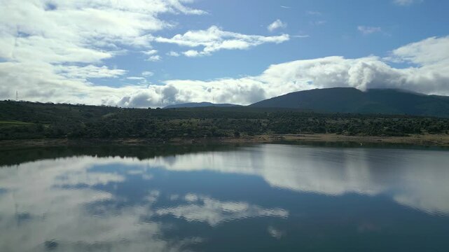 Sun rising through the clouds at dawn and reflections in the water of a lake of calm water, El Atazar.