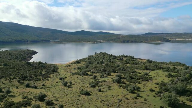 Beautiful lake of calm water and reflections of the blue sky with storm clouds, El Atazar, Madrid.