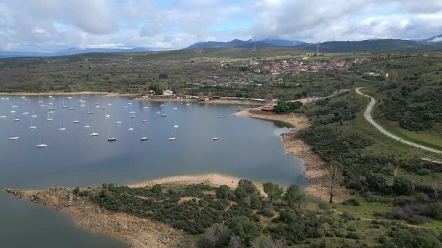Beautiful lake next to the mountains with small pleasure boats at the foot of the houses, El Atazar, Cervera, Madrid.