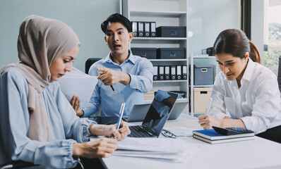 Young asian businesswoman suffering from headache while colleagues arguing and blaming her for bad...