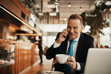 Confident businessman working remotely at coffee shop while drinking espresso