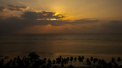 wsch&oacute;d słońca nad oceanem indyjskim, spokojne wody odbijają poranne promienie a przybrzeżne tropikalne palmy uzupełniają piękny widok, Kenia, Afryka