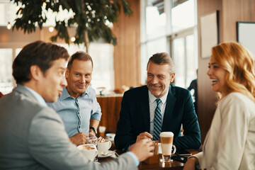 Group of business professionals laughing and networking at coffee shop meeting