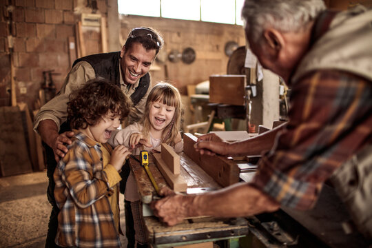 Happy multigenerational family building wooden project together in home workshop