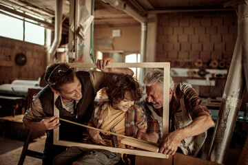 Three male generations working together on a woodworking project in family workshop