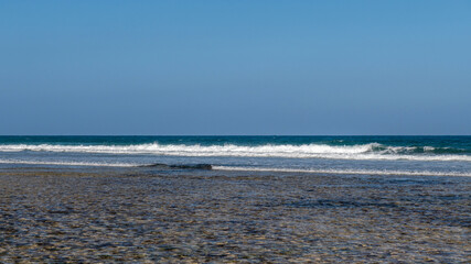 początek przypływu, łagodne fale oceanu indyjskiego przelewają się przez rafę koralową do laguny otaczającej wybrzeże Kenii. Okolice Mombasy, Kikambala, Kenia, Afryka