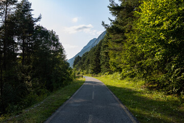 Fototapeta premium vista panoramica su parte della lunga pista ciclabile Alpeadria, a fondovalle, in mezzo alle montagne, nel Friuli Venezia Giulia nord-orientale, di giorno, con cielo sereno, in estate