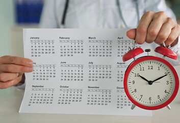 A healthcare professional is showing a calendar while holding an alarm clock. This represents the...