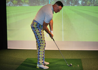 Golfer practices swing indoors virtual golf simulator