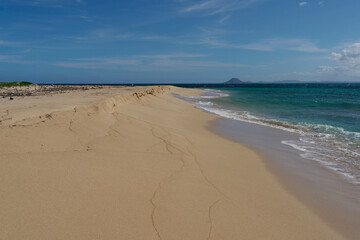 A sandy beach on one of the Seven Brothers Islands with El Morro Mountain in the background.