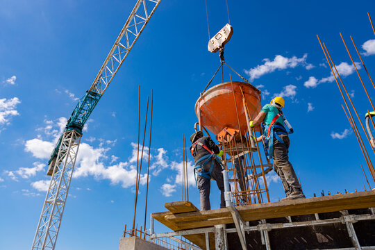 Masons fill up vertical mold with help of crane as carry cone tank for cement mixture