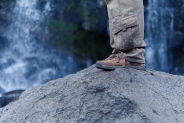 Hiker standing on rock overlooking waterfall in apatlaco, mexico