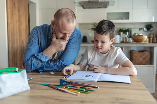 Angry father yell at his son to do homework as soon as possible. xhausted father help son to finish his homework while son have attention deficit disorder and dont want to study anymore.