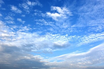 A group of birds is flying in the blue sky to the east, surrounded by clouds near the moon.