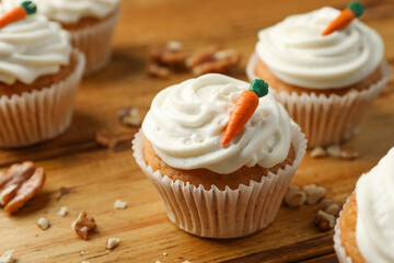 Delicious carrot cupcakes and walnuts on wooden table, closeup