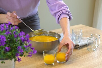 Cooking mango and chia seeds dessert. Step-by-step recipe. A woman pours mango puree into glasses