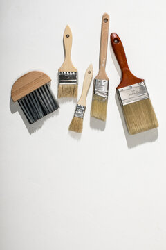 Paint brushes on white plaster surface