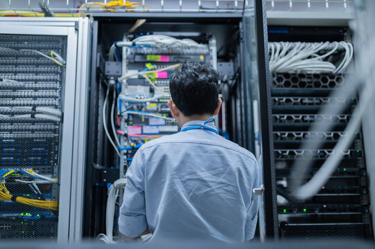 Computer engineer is setting up network in server room,Systems Maintenance Technician,Male engineer working in server room at modern data center