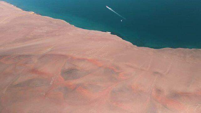 Aerial View of the Andean Candelabra Geoglyph and Desert Coastline, Paracas, Peru. This captivating aerial footage showcases the famous Andean Candelabra geoglyph carved into the desert 