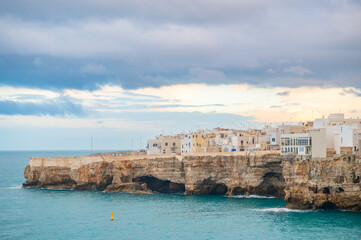 Obraz premium View of houses on cliff in Polignano a Mare at sunset, Puglia, Italy. Travel photography. Golden hour landscape.